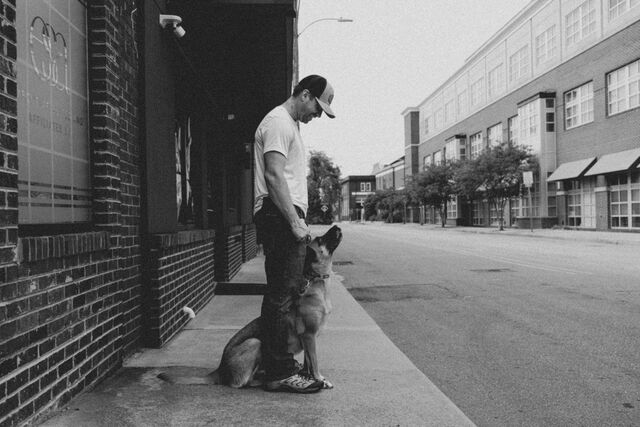 Black-and-white photograph of a seated dog looking up at a trainer