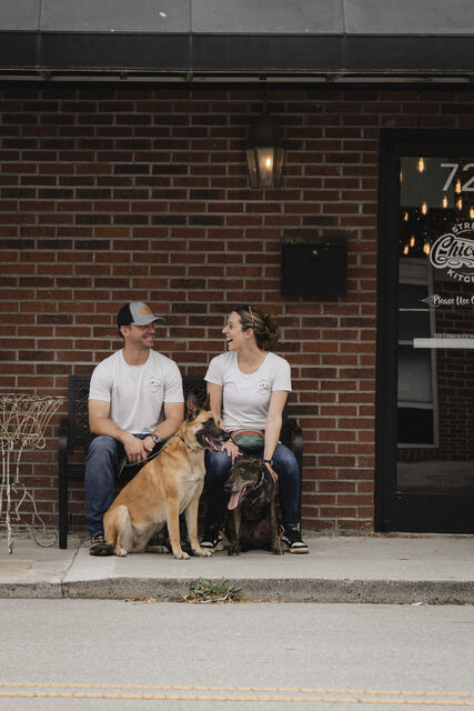 Two trainers sitting on a bench with two dogs
